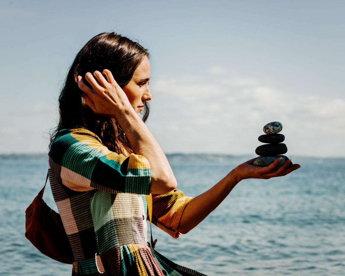 Woman Balancing stones in her hand on the beach