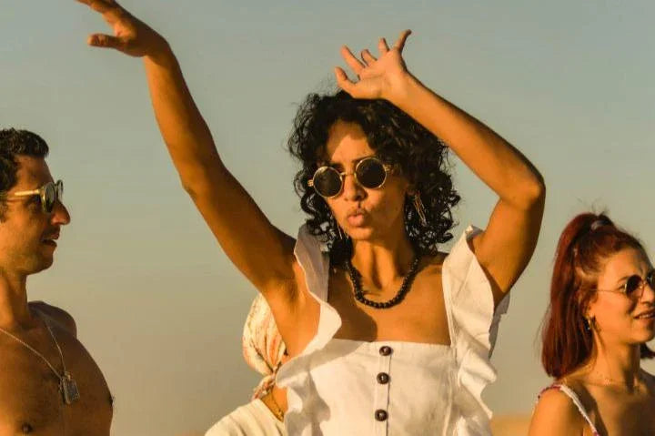 Group of friends dancing outdoors in warm sunlight, expressing carefree energy, freedom, and living fully in the moment.